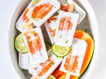 a bowl filled with coconut lime and papaya popsicles with lime slices