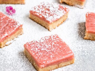 vegan shortbread cookie bars topped with a rhubarb curd layer and powdered sugar