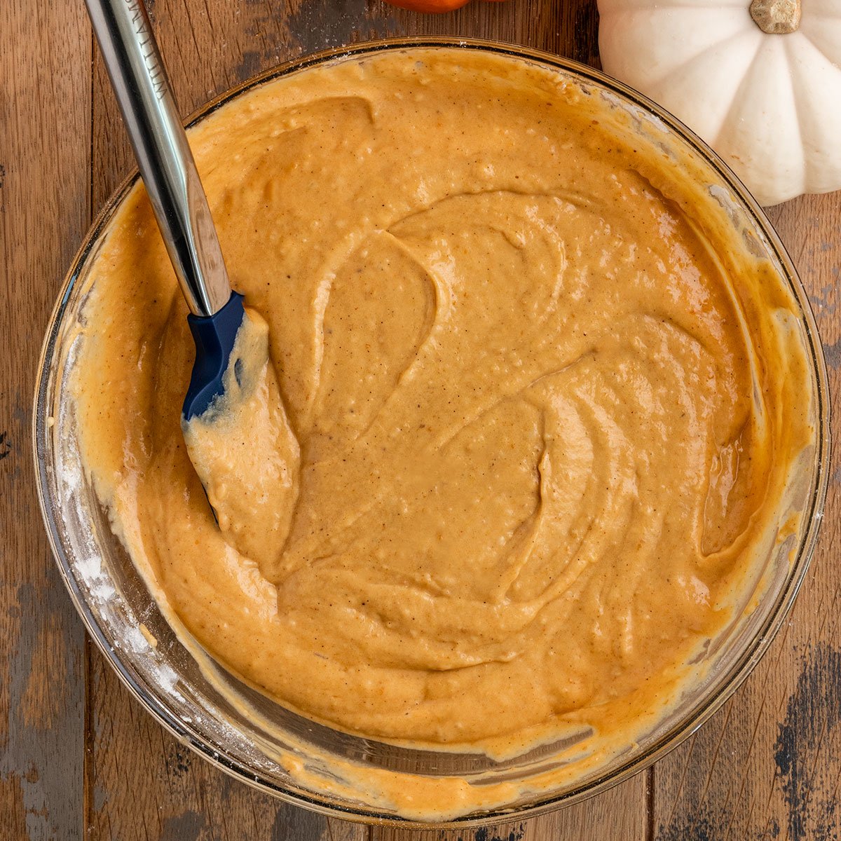 mixing bowl with pumpkin cake batter and spatula.