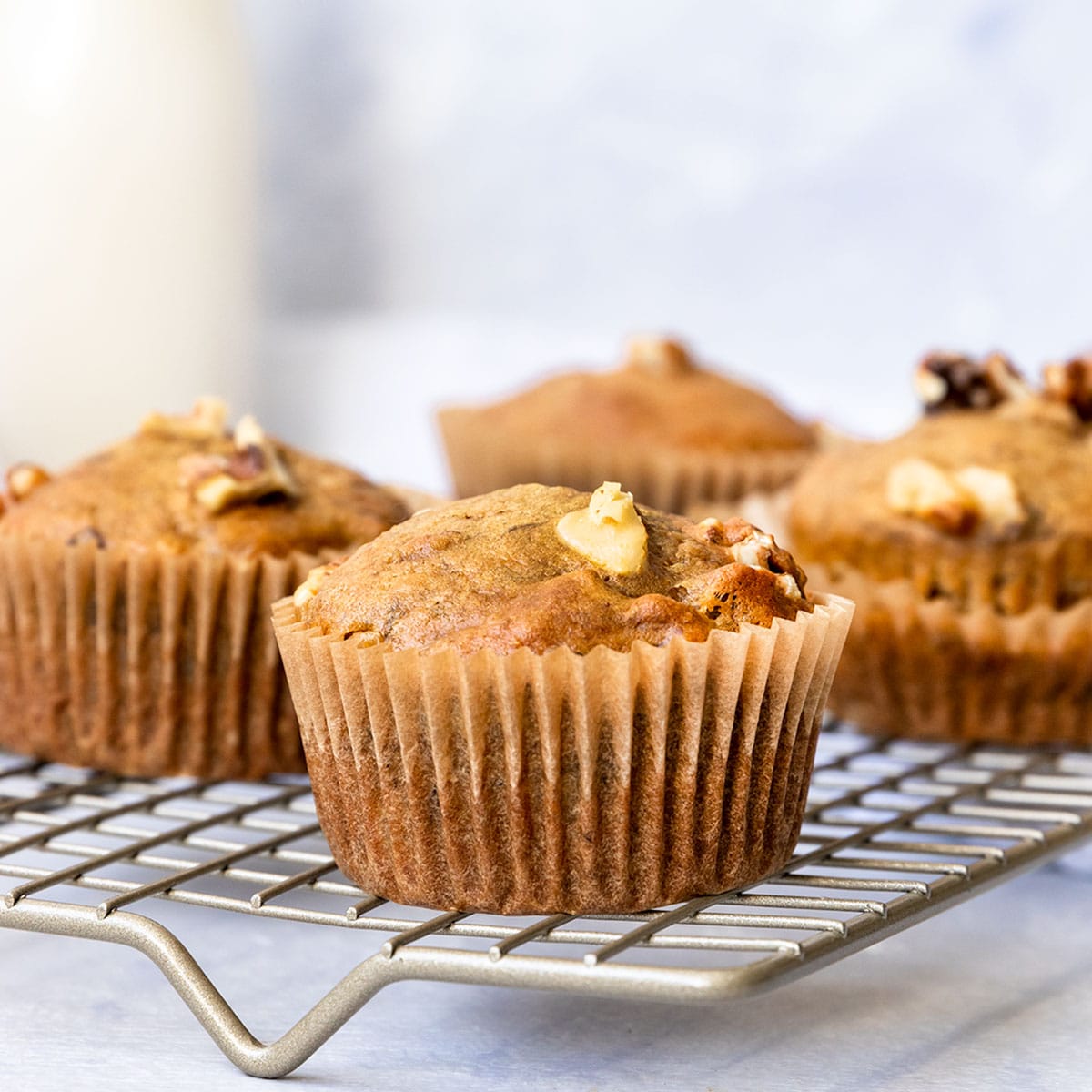 wire rack filled with banana walnut muffins and a glass of milk