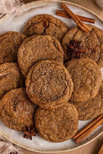 brown sugar cookies stacked on a plate surrounded by star anise and cinnamon sticks.