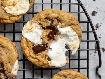 wire cooling rack with smores cookies on it filled with chocolate chunks and melted marshmallows