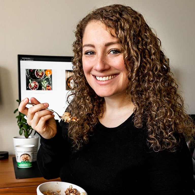 photo of girl holding spoon in front of computer.