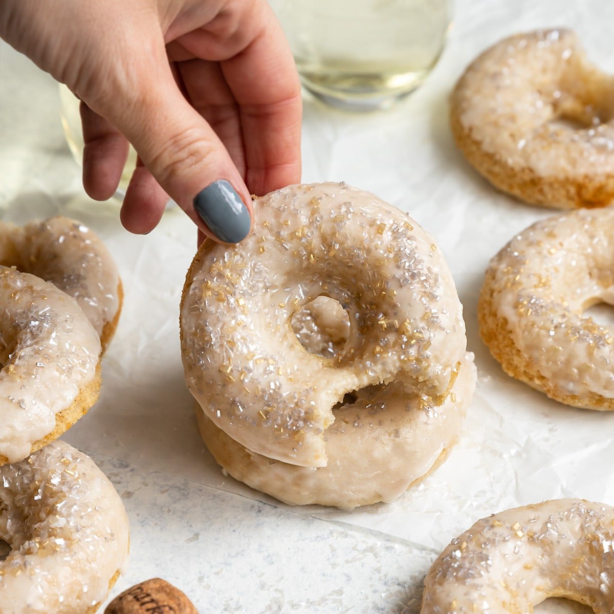hand lifting up a doughnut from a pile of donuts