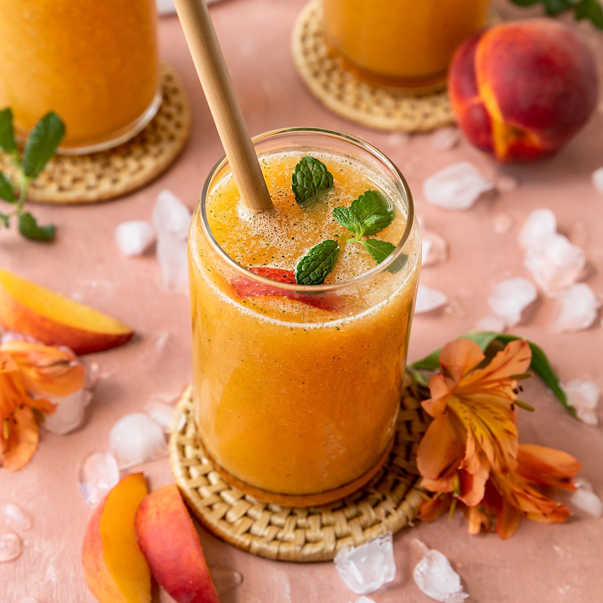 a frozen peach cocktail garnished with peach slices and mint on top