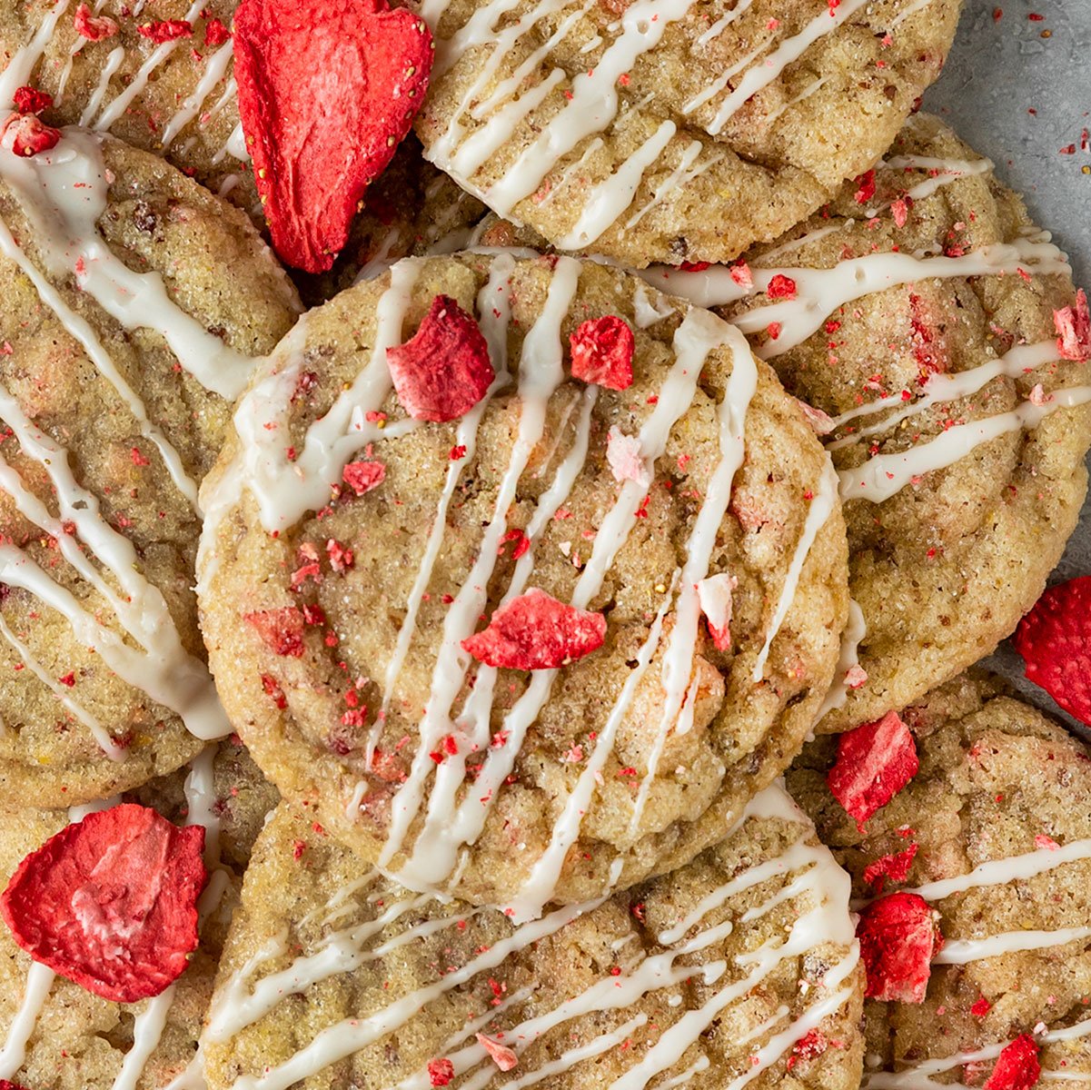 pile of cookies topped with vanilla icing and dried strawberry pieces