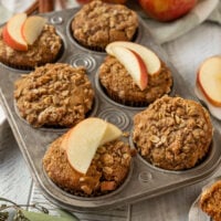 pan of muffins with streusel topping and apple slices on top