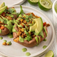 two stuffed sweet potatoes with cilantro lime crema and avocado on top