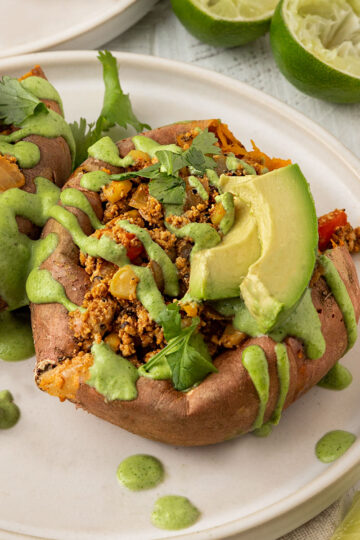 two stuffed sweet potatoes with cilantro lime crema and avocado on top