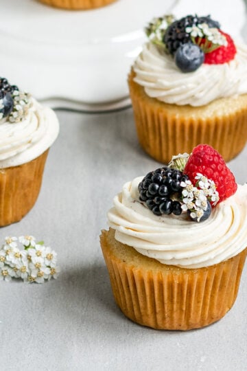 cupcakes with vanilla frosting, blueberries, blackberries, and raspberries on top.