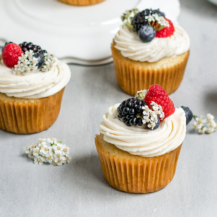 cupcakes with vanilla frosting, blueberries, blackberries, and raspberries on top.