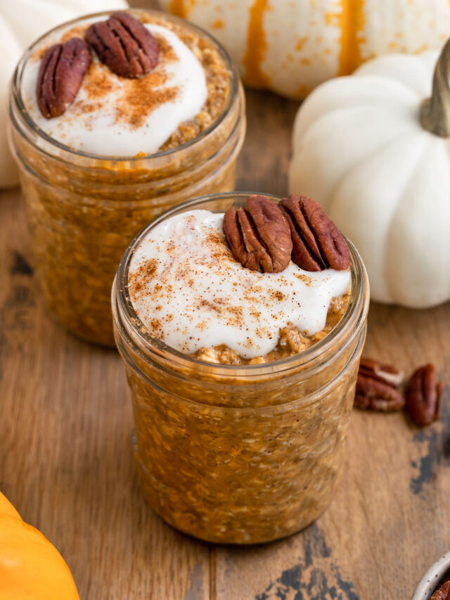 two containers of pumpkin oats with yogurt and pecans on top.