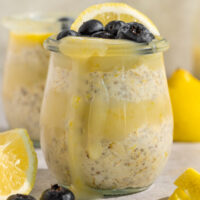 glass container with oatmeal, lemon curd, blueberries, and fresh lemon slices.