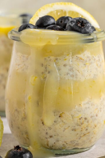 glass container with oatmeal, lemon curd, blueberries, and fresh lemon slices.