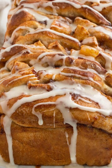 apple fritter bread with apple chunks and glaze on a platter.