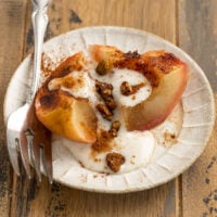 baked apple filled with yogurt and granola cut in half.