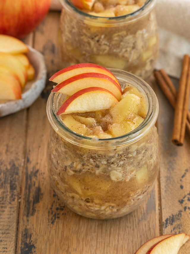 glass of apple pie oats with cooked apple chunks and fresh apple slices on top.