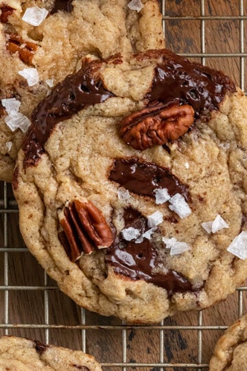 cookies with pecans and chocolate chunks on a wire rack with bourbon and pecans.