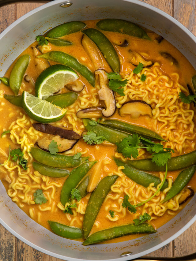 pot of ramen with curry broth, shiitake mushrooms, snap peas, cilantro, and limes.