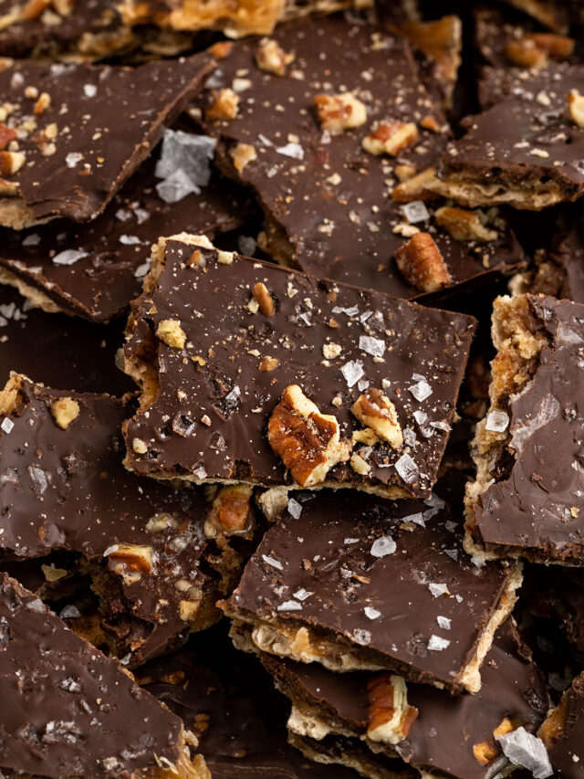 a pile of of chocolate and toffee covered matzah pieces with pecans and sea salt on top.