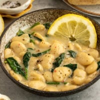 bowl of creamy butter beans with lemon garlic and spinach and side of toast.