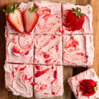 sliced strawberry cake topped with strawberry frosting strawberry puree and fresh strawberries.