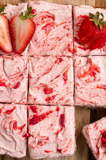 sliced strawberry cake topped with strawberry frosting strawberry puree and fresh strawberries.