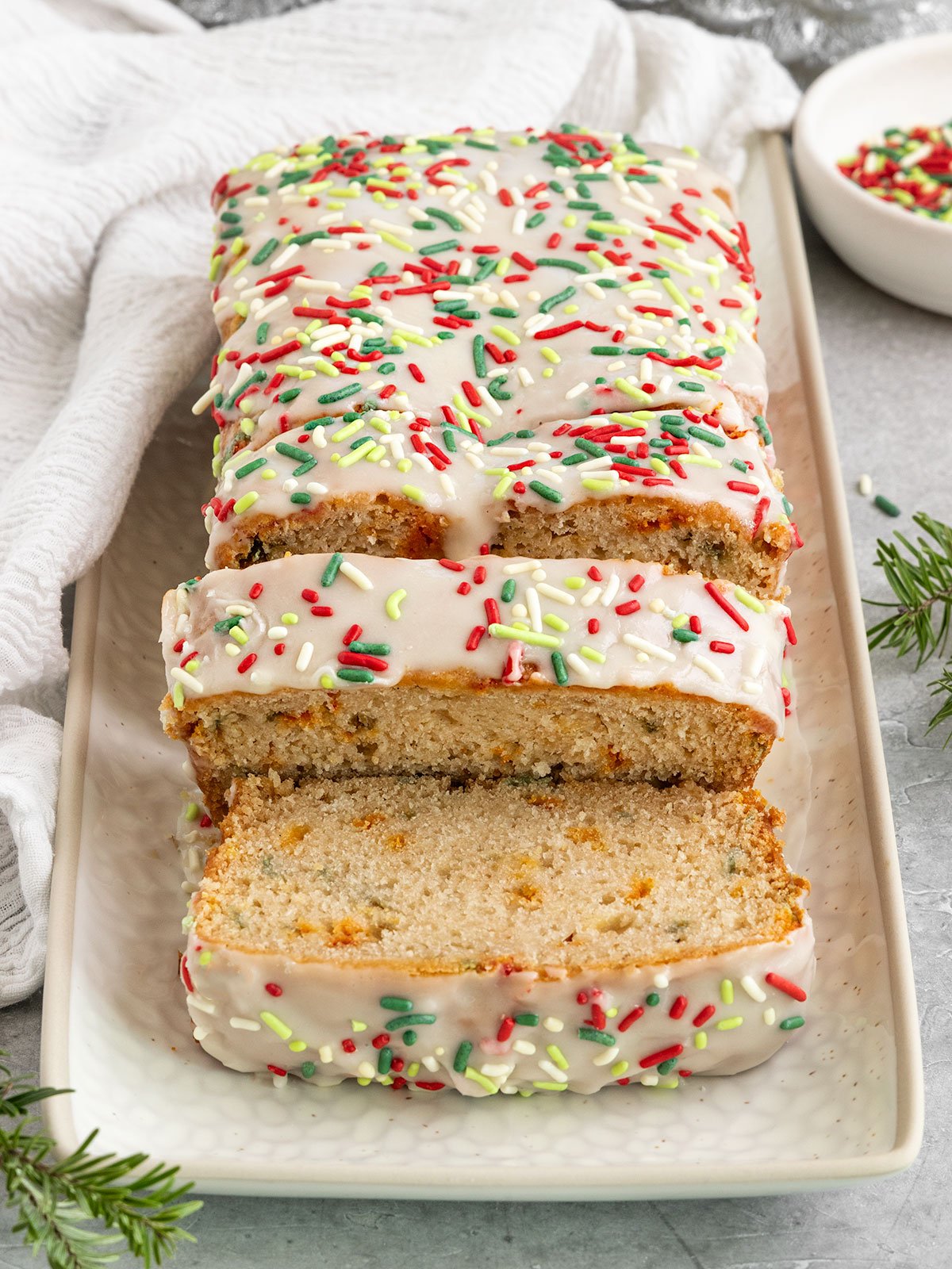 sliced loaf of bread on tray with green and red rainbow sprinkles and icing on top.