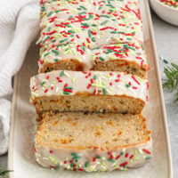 sliced loaf of bread on tray with green and red rainbow sprinkles and icing on top.