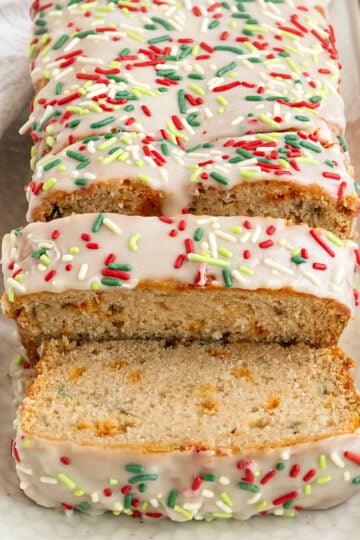 sliced loaf of bread on tray with green and red rainbow sprinkles and icing on top.