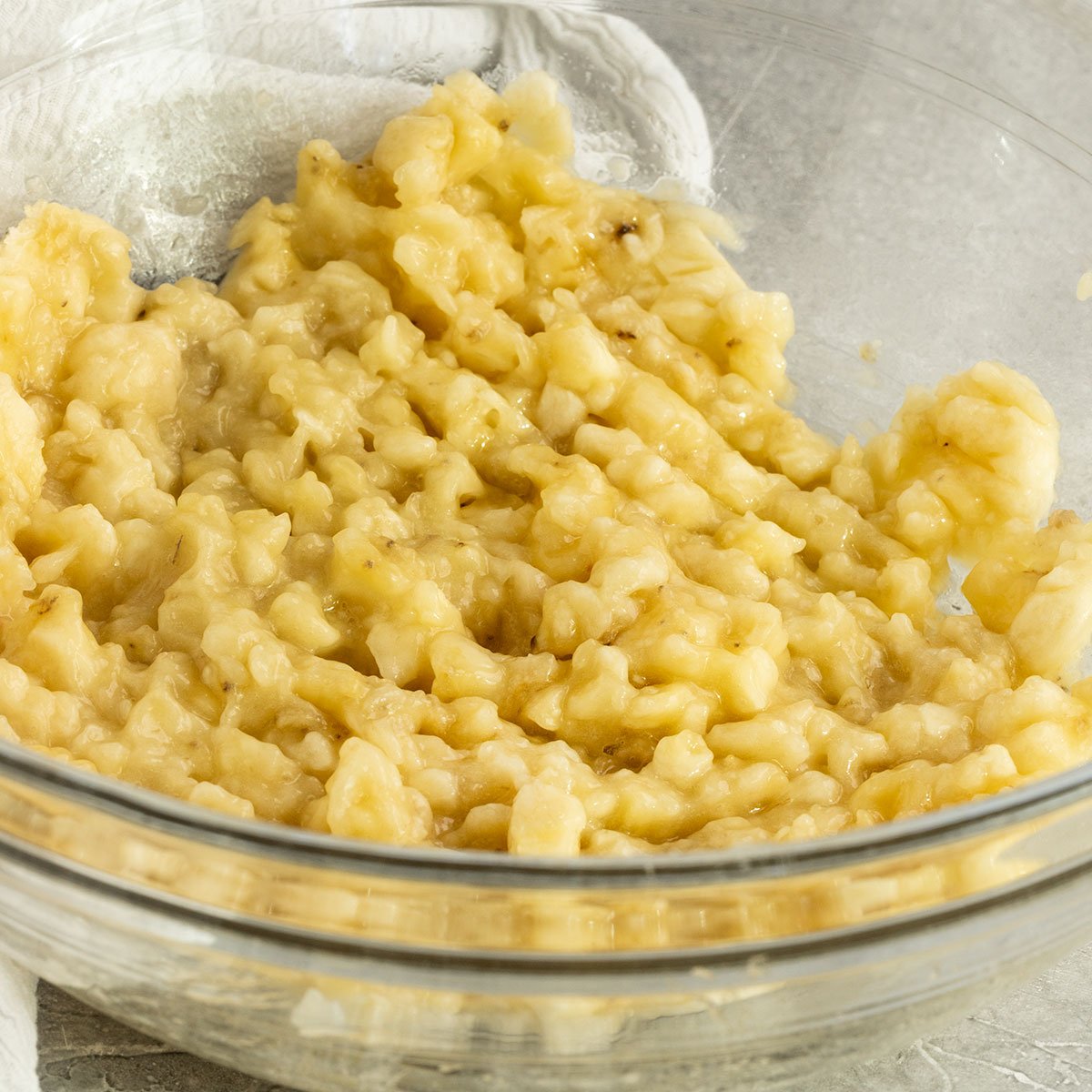 mashed bananas in glass mixing bowl.