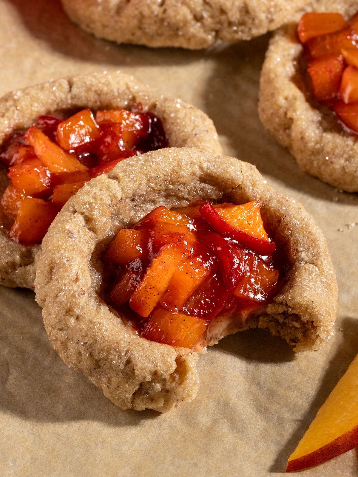 peach pie cookies with a bite taken out to show gooey inside and chewy cookie exterior.