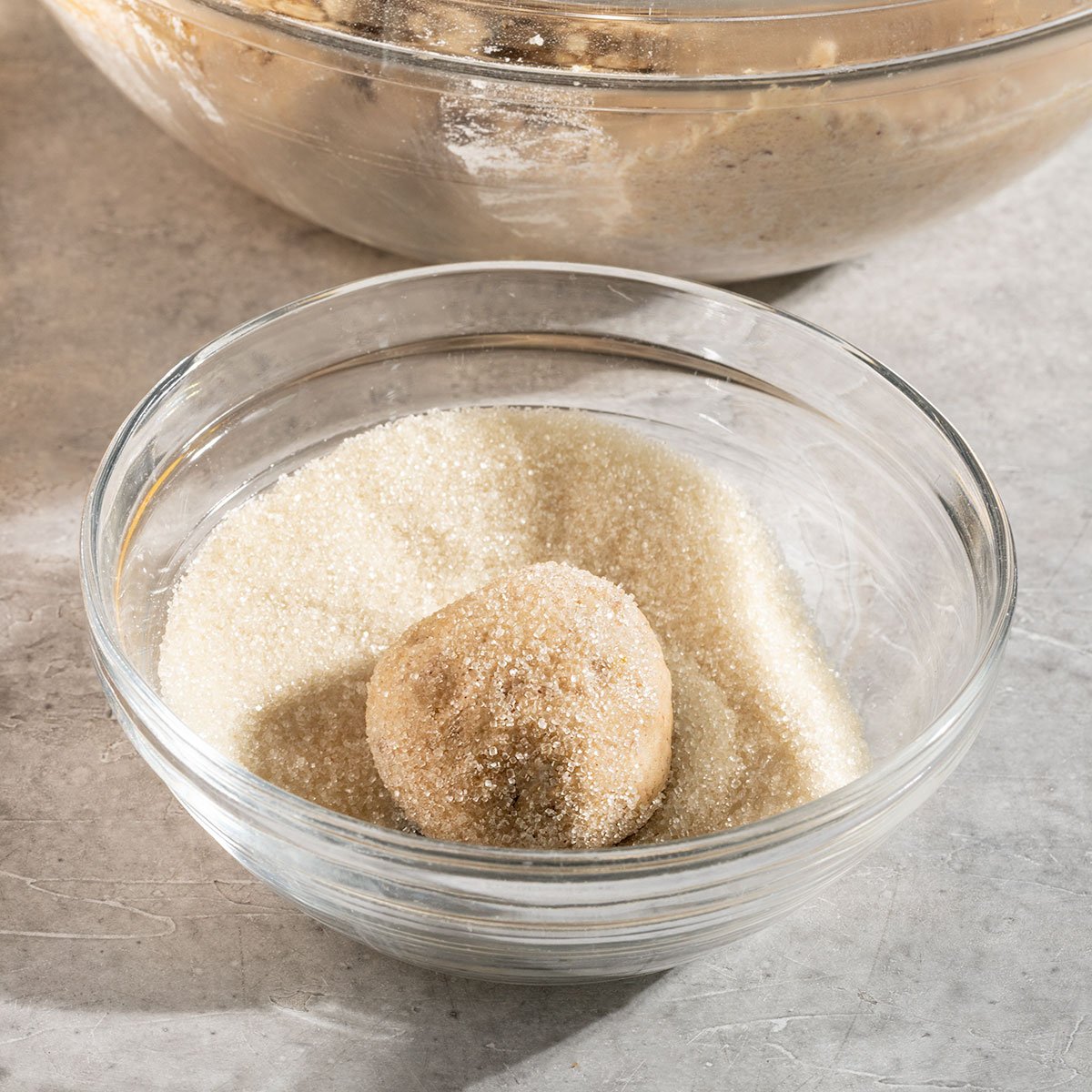 rolling cookie dough balls in a bowl of sugar.