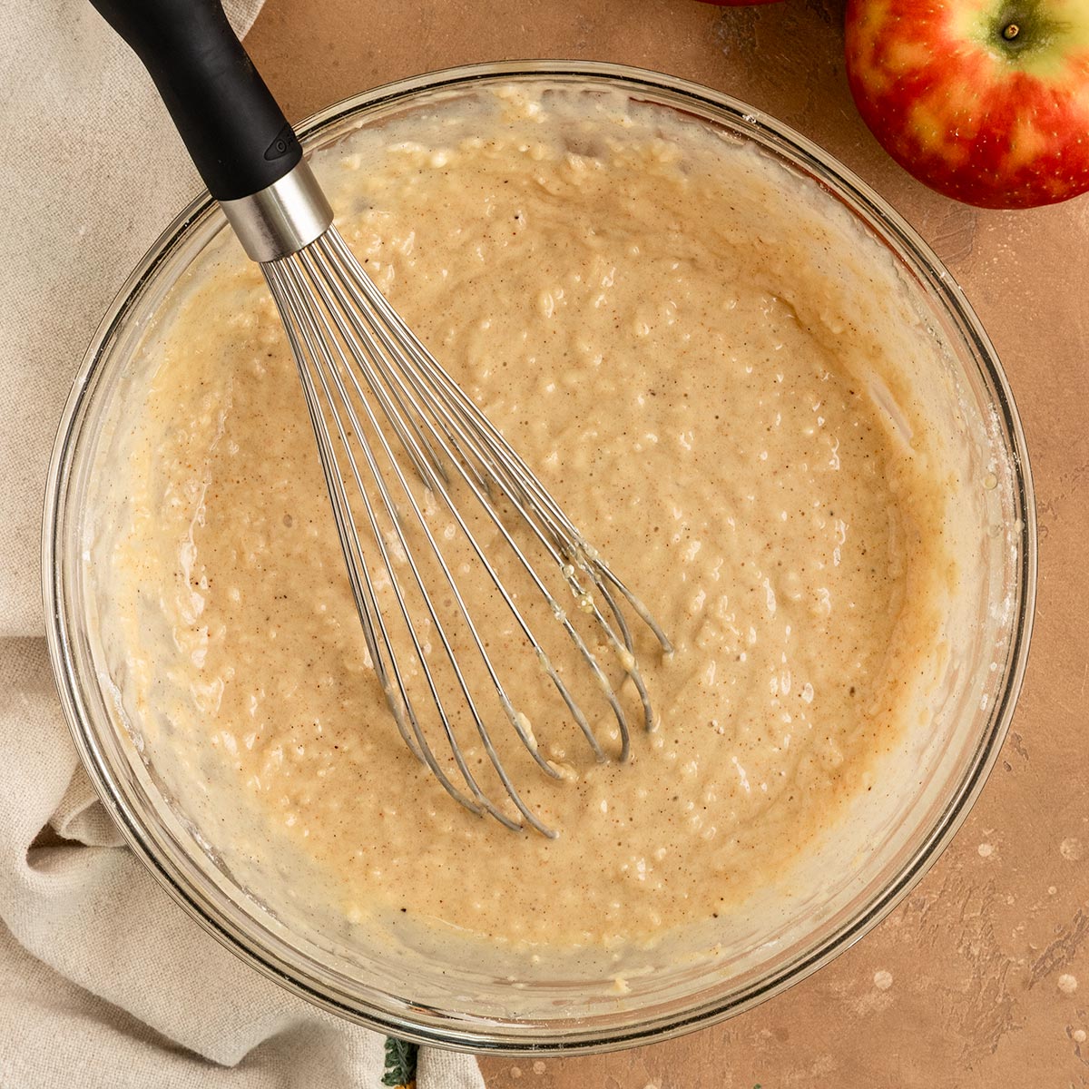 apple cake batter in a mixing bowl with spatula.