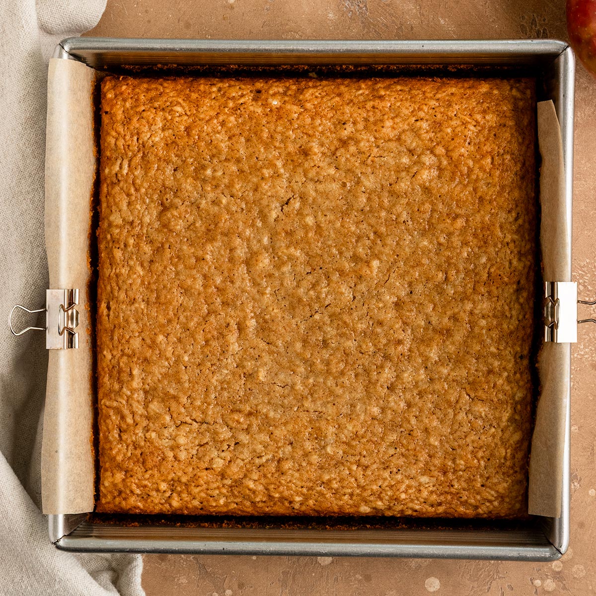 baked apple cake in a square baking dish with parchment paper.
