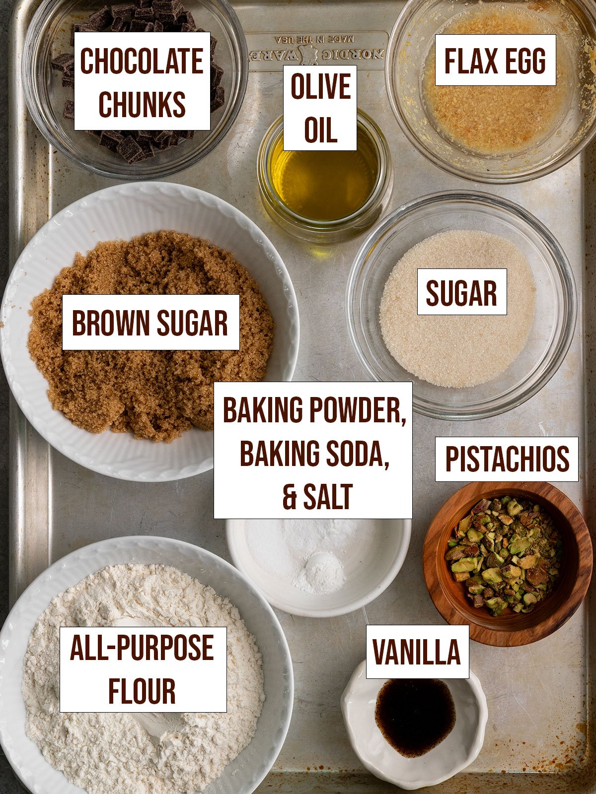 labeled ingredients for olive oil cookies with flour, chocolate, pistachio, olive oil, vanilla, brown sugar, sugar, baking powder, baking soda, and salt.