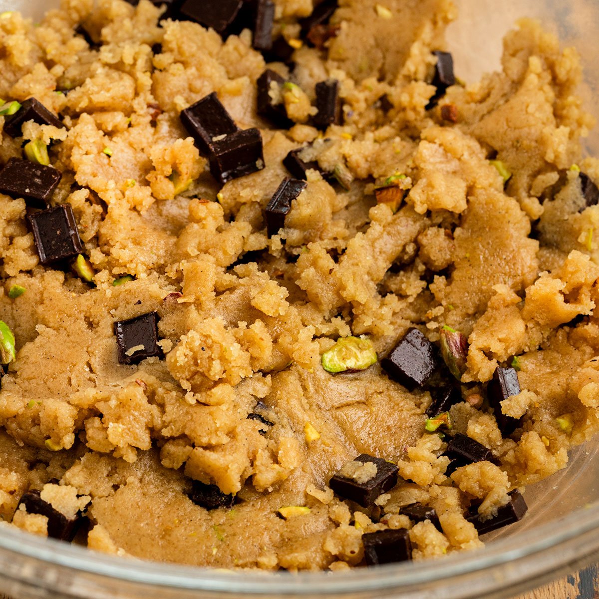 bowl of cookie dough batter with olive oil, pistachios, chocolate chunks.