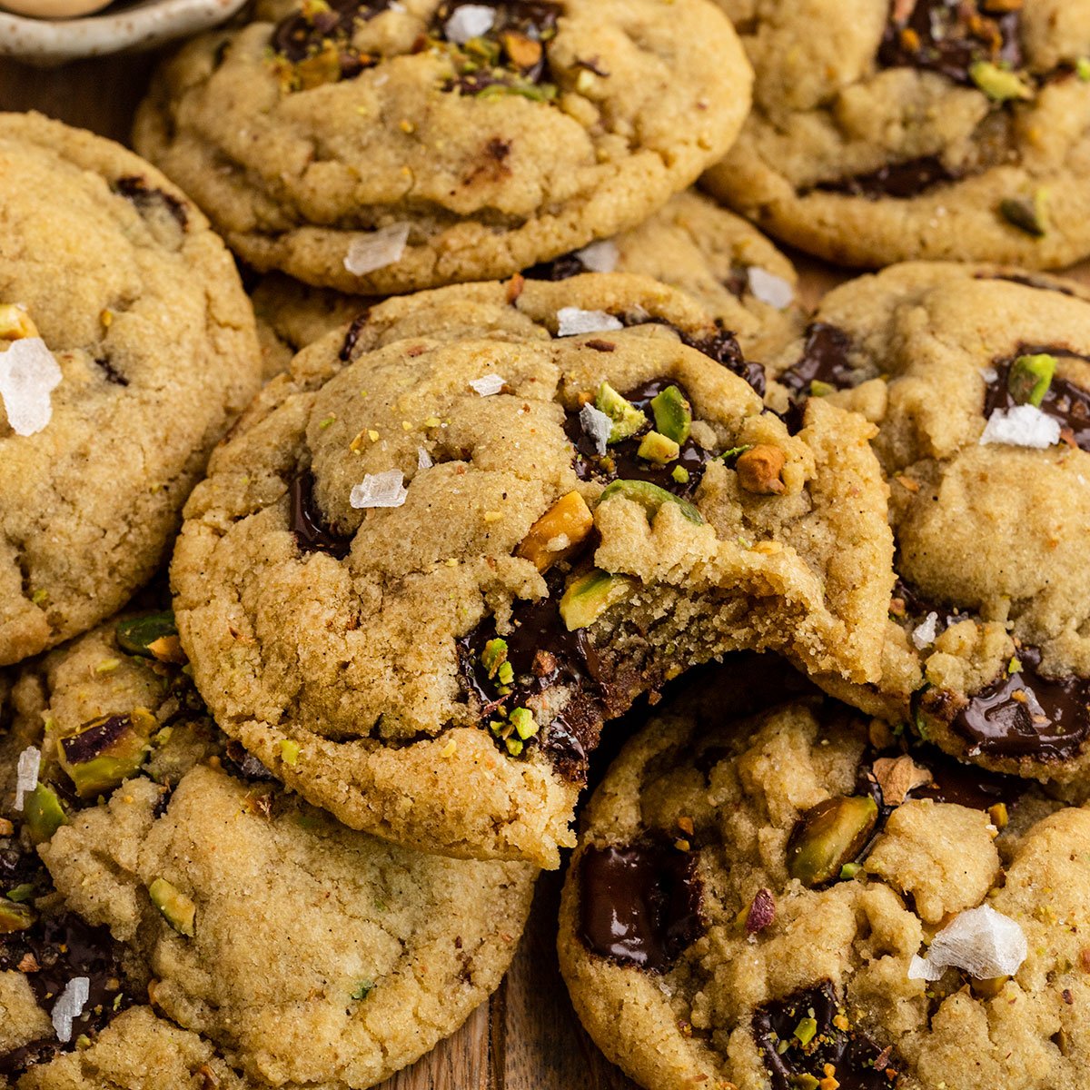 cookies with olive oil pistachios and flaky sea salt with top cookie missing a bite.
