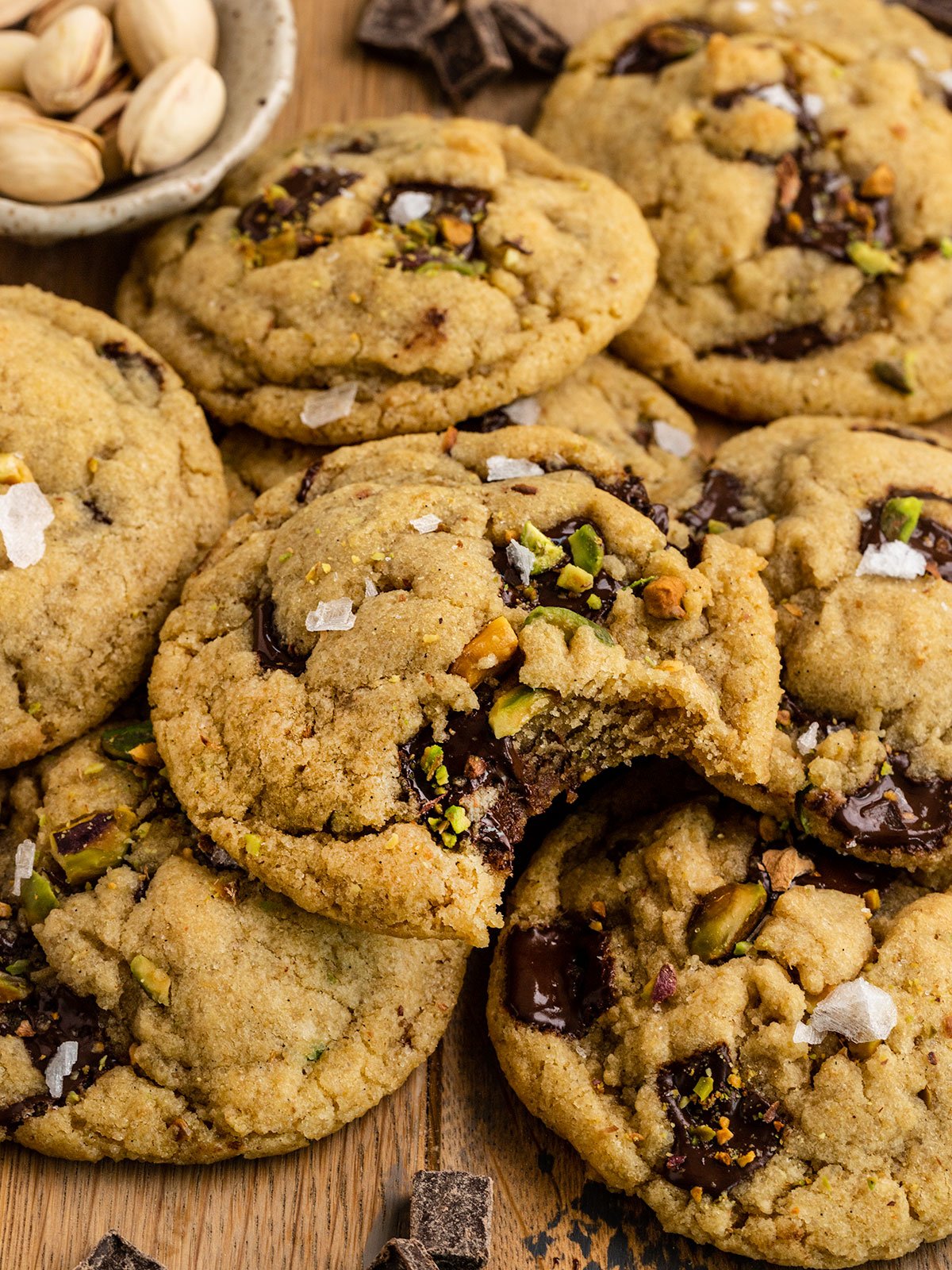 cookies with olive oil pistachios and flaky sea salt with top cookie missing a bite.