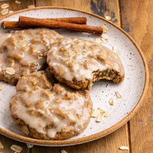 oatmeal cookies with icing on top on a plate with cinnamon sticks.