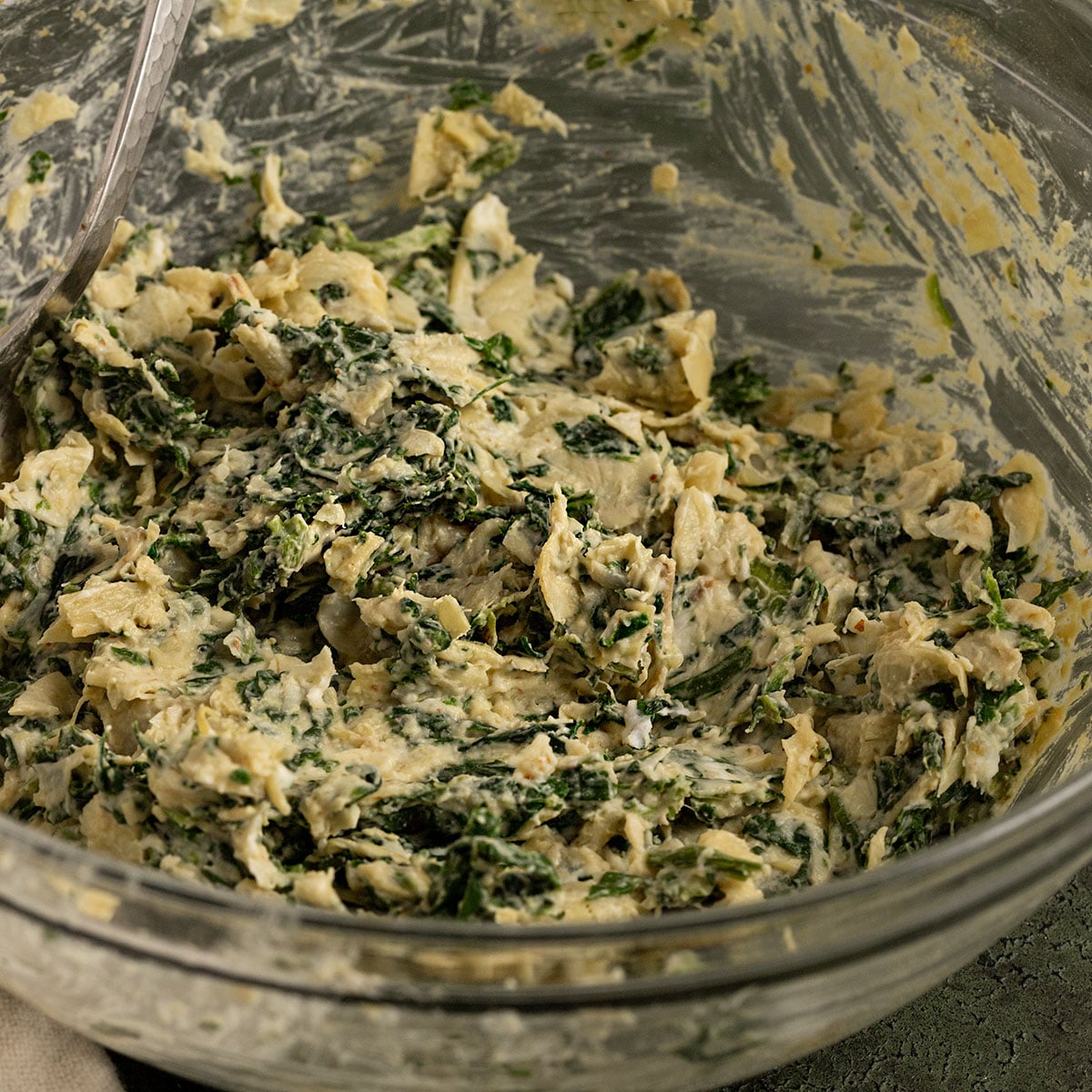 bowl of spinach artichoke cream cheese filling mixed together.