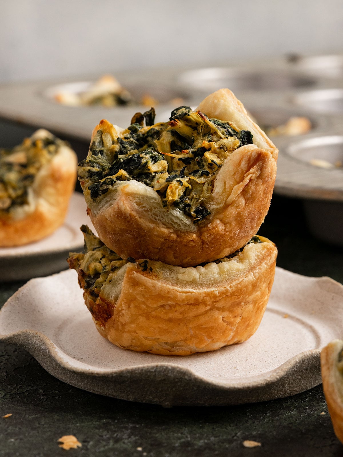 two puff pastries filled with spinach artichoke cream stacked on a plate.