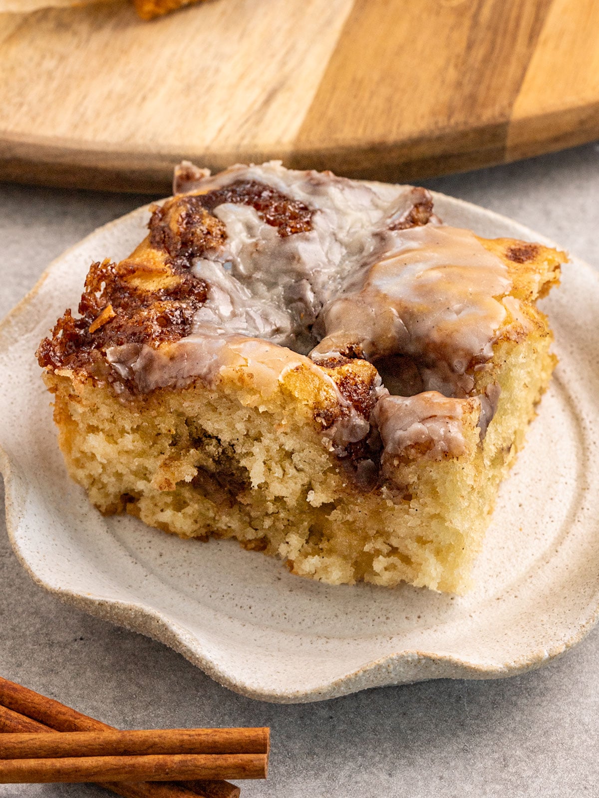 slice of vanilla cake with pools of cinnamon sugar inside and a vanilla icing on top on a ruffled plate.