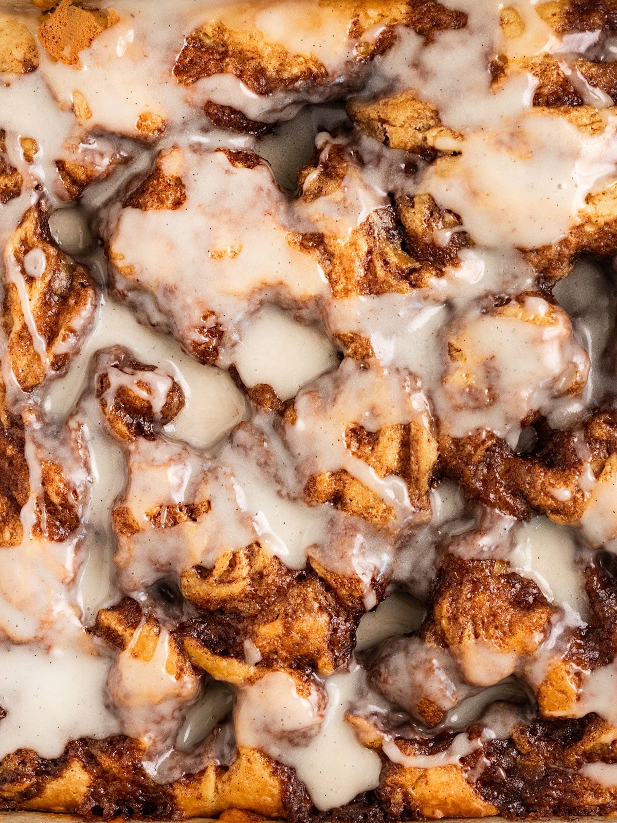 overhead shot of a cake with pools of cinnamon sugar and a vanilla icing on top.