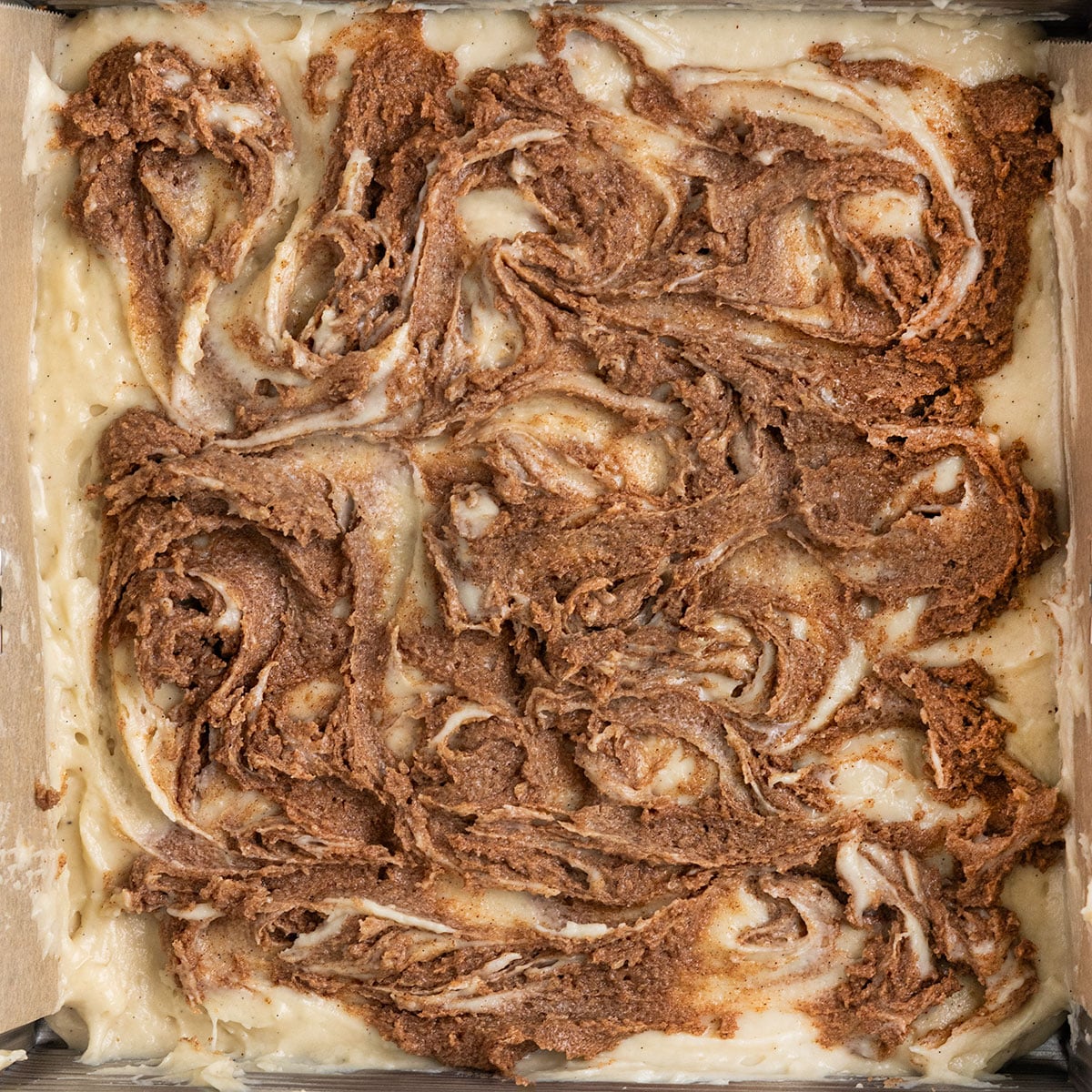 pan with vanilla cake batter and swirls of cinnamon sugar before baking.