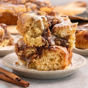 two slices of cake filled with cinnamon sugar and topped with vanilla icing stacked on top of each other on a small plate.