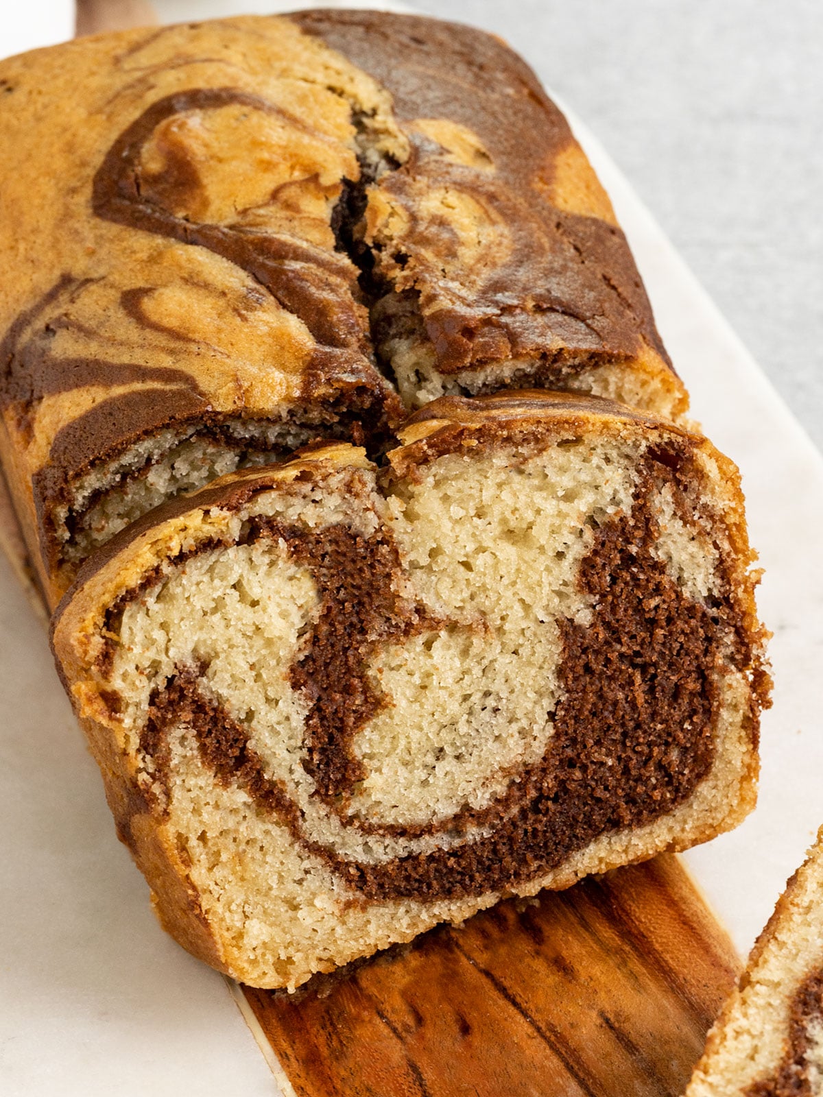 sliced chocolate vanilla marbled swirl loaf cake on a marble board.