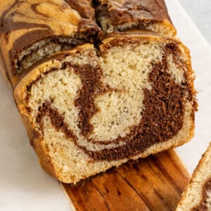 sliced chocolate vanilla marbled swirl loaf cake on a marble board.