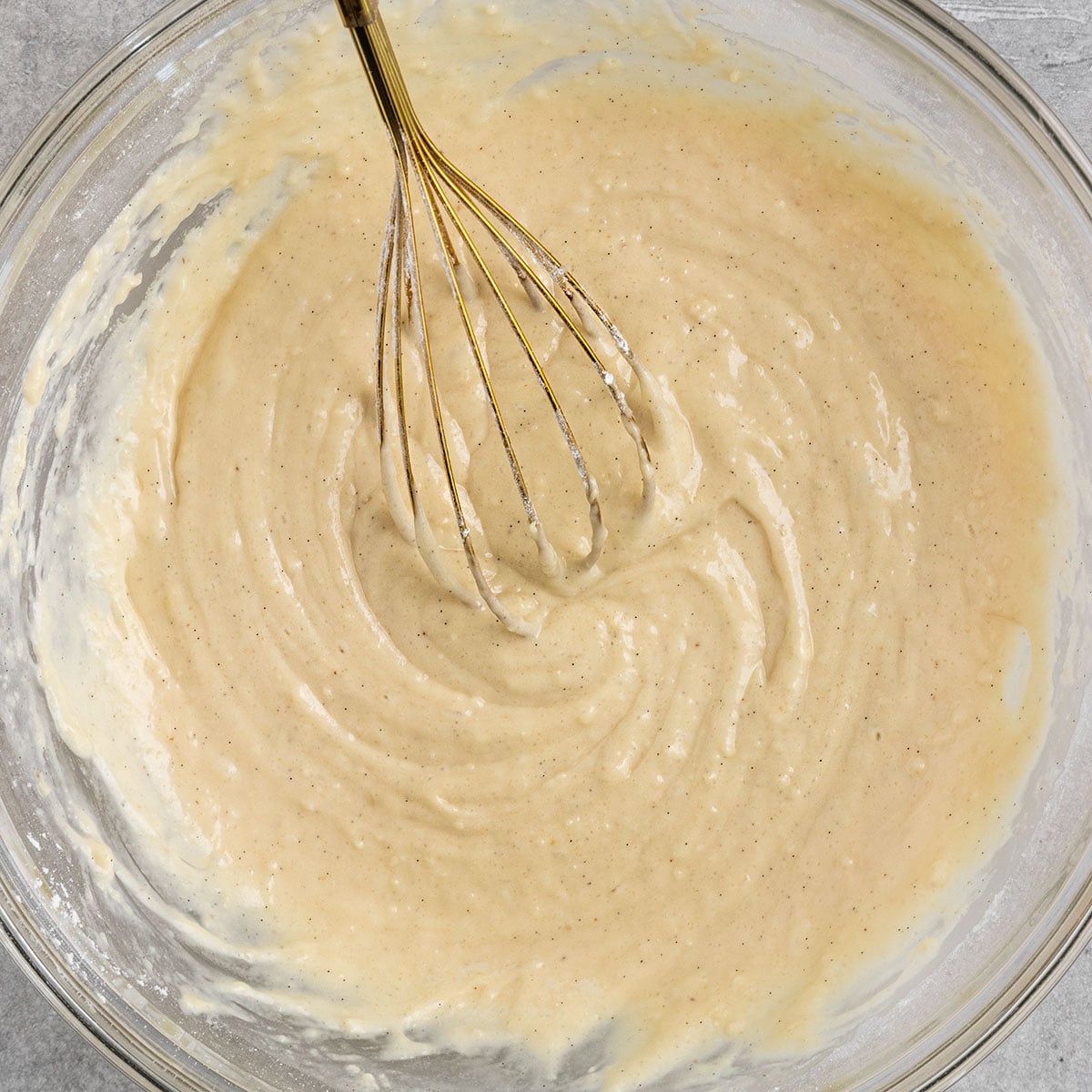 bowl of vanilla cake batter with whisk in the bowl.