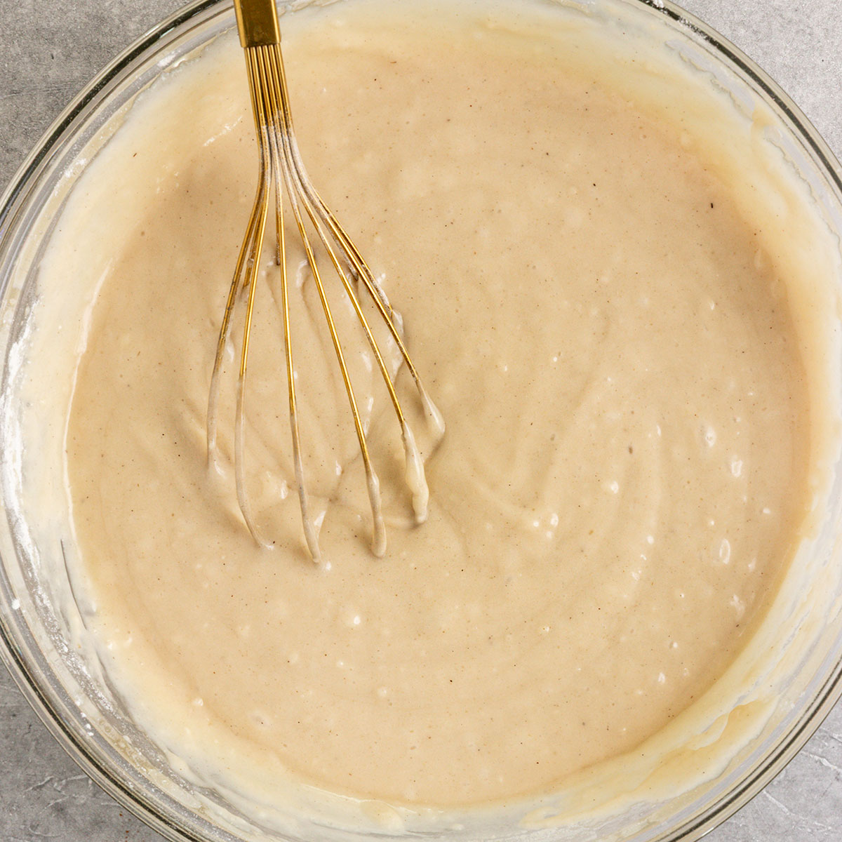 vanilla cake batter in a bowl with a whisk.